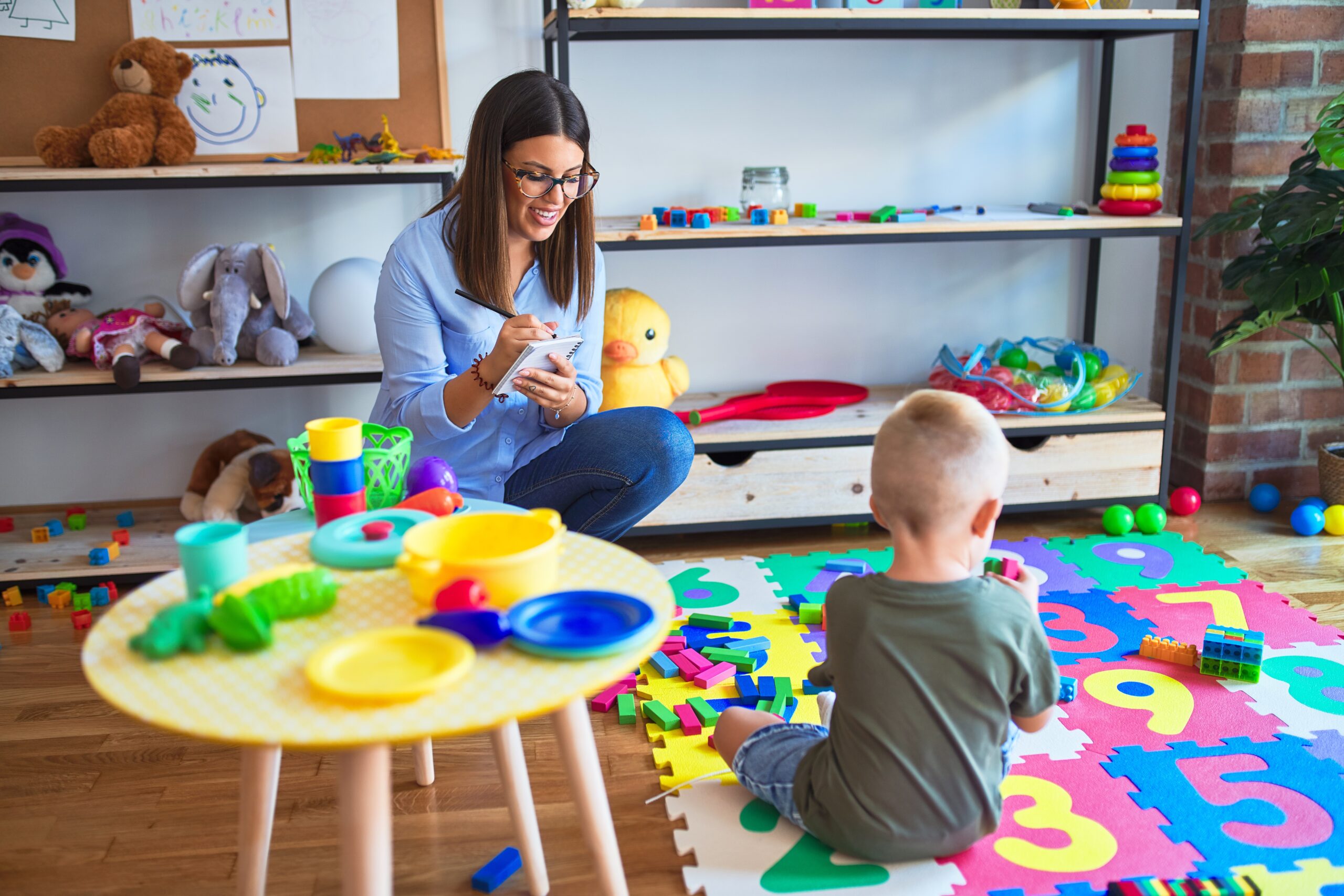 Young therapist woman speaking with child, counselor and behaviour correction at the office around toys