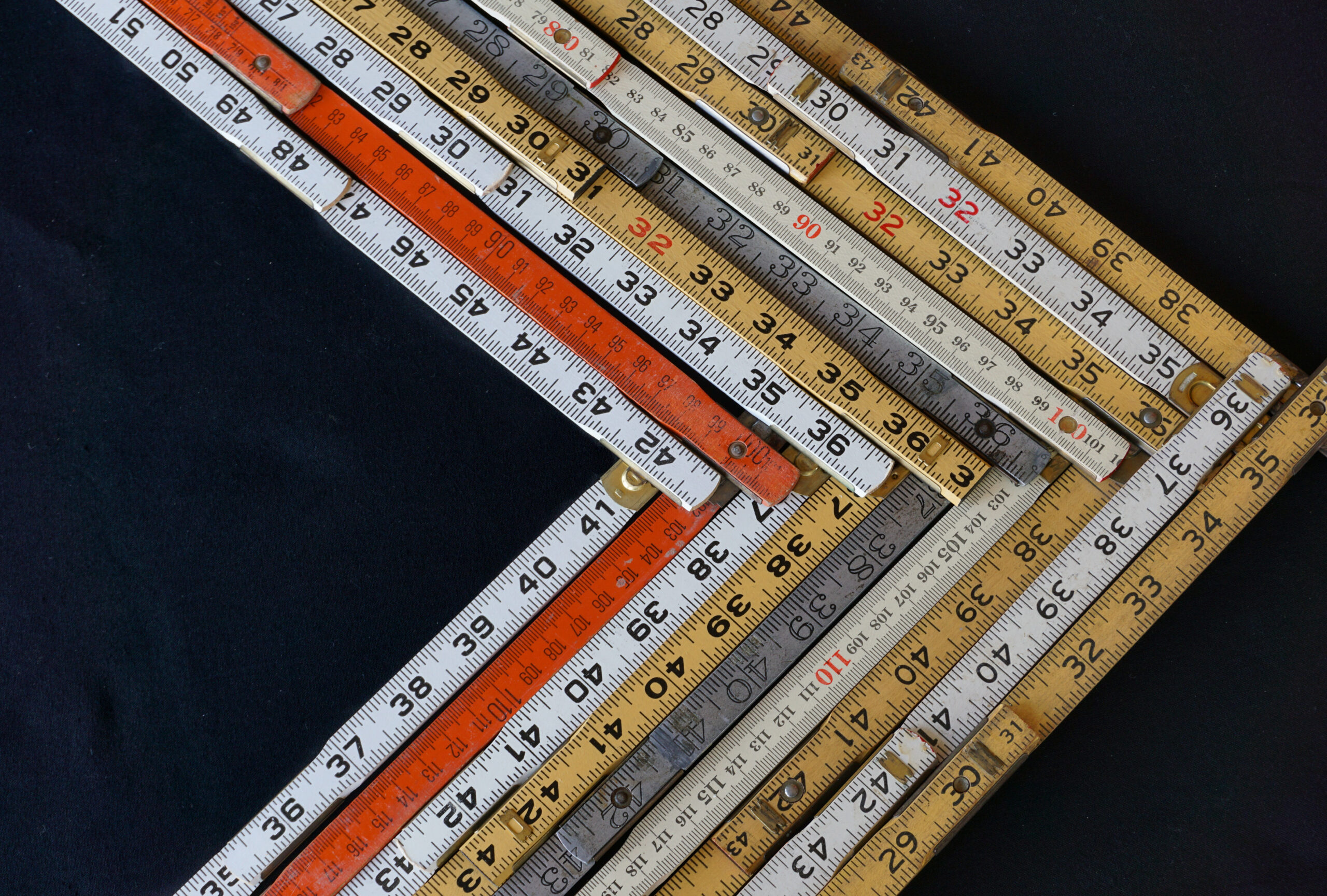 Folding rulers in metric and inches on black background form a c