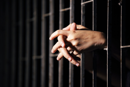 hands of prisoner in jail as background.