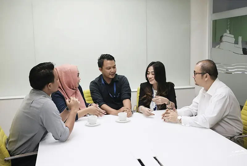 A group of people converse at one end of a conference table