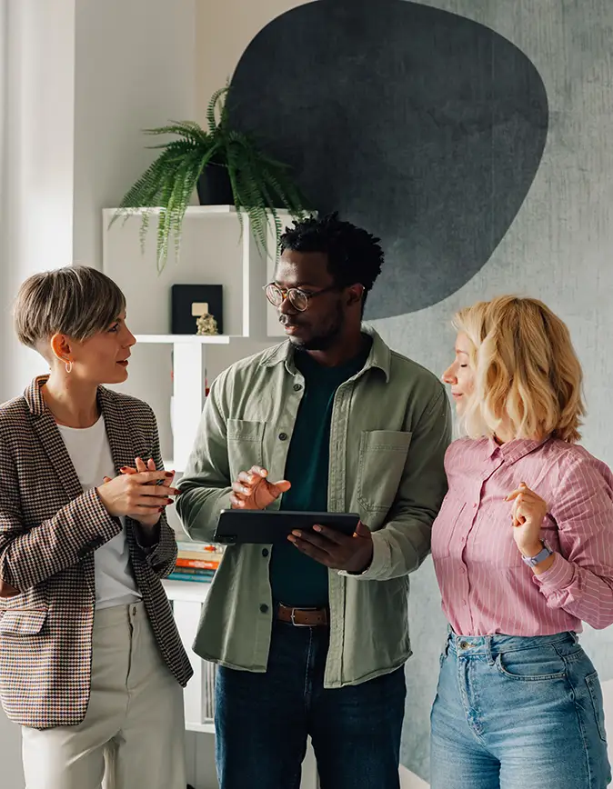 Three young professionals talk in an office setting