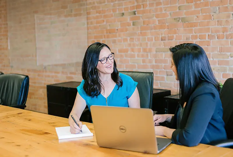 Two women chat at a conference table