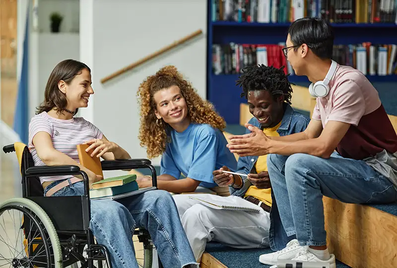A diverse group of students chat in a library