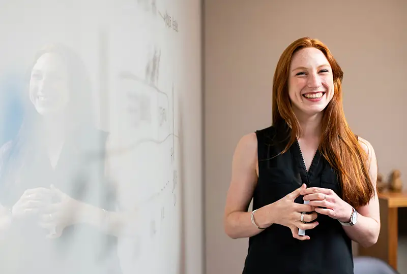 A young woman stands in front of a whiteboard