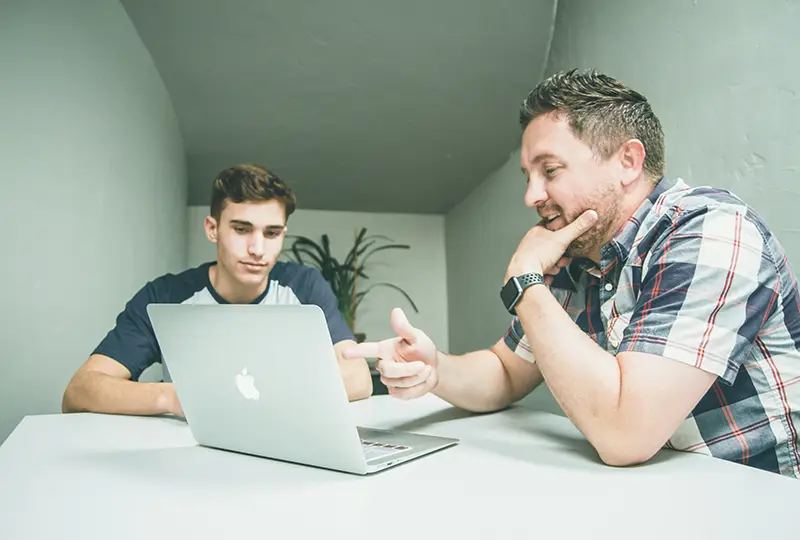 Two men of different ages look at a computer screen